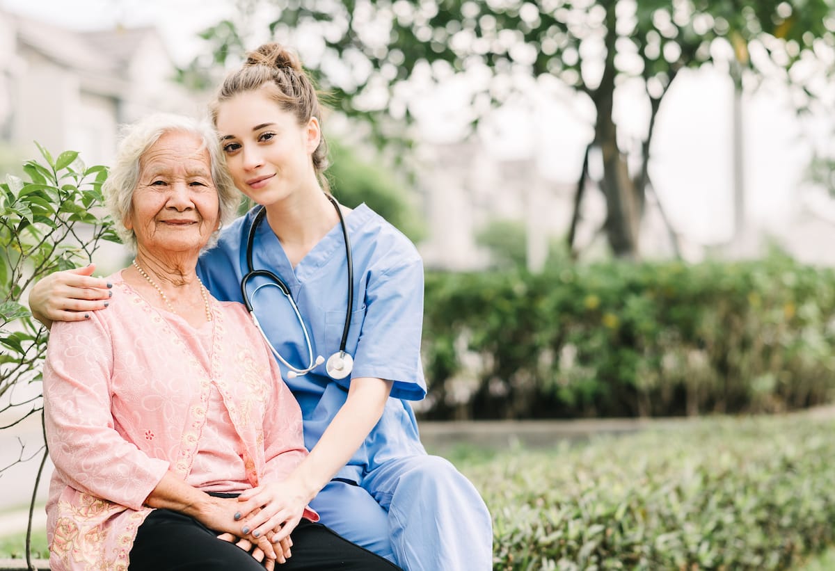 An elderly woman sitting next to a caregiver