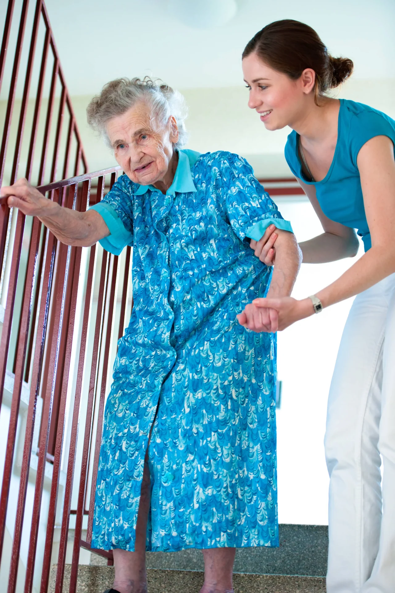 An elderly person holding onto a banister standing on stairs, assisted by a caregiver at a in home care services Chicago