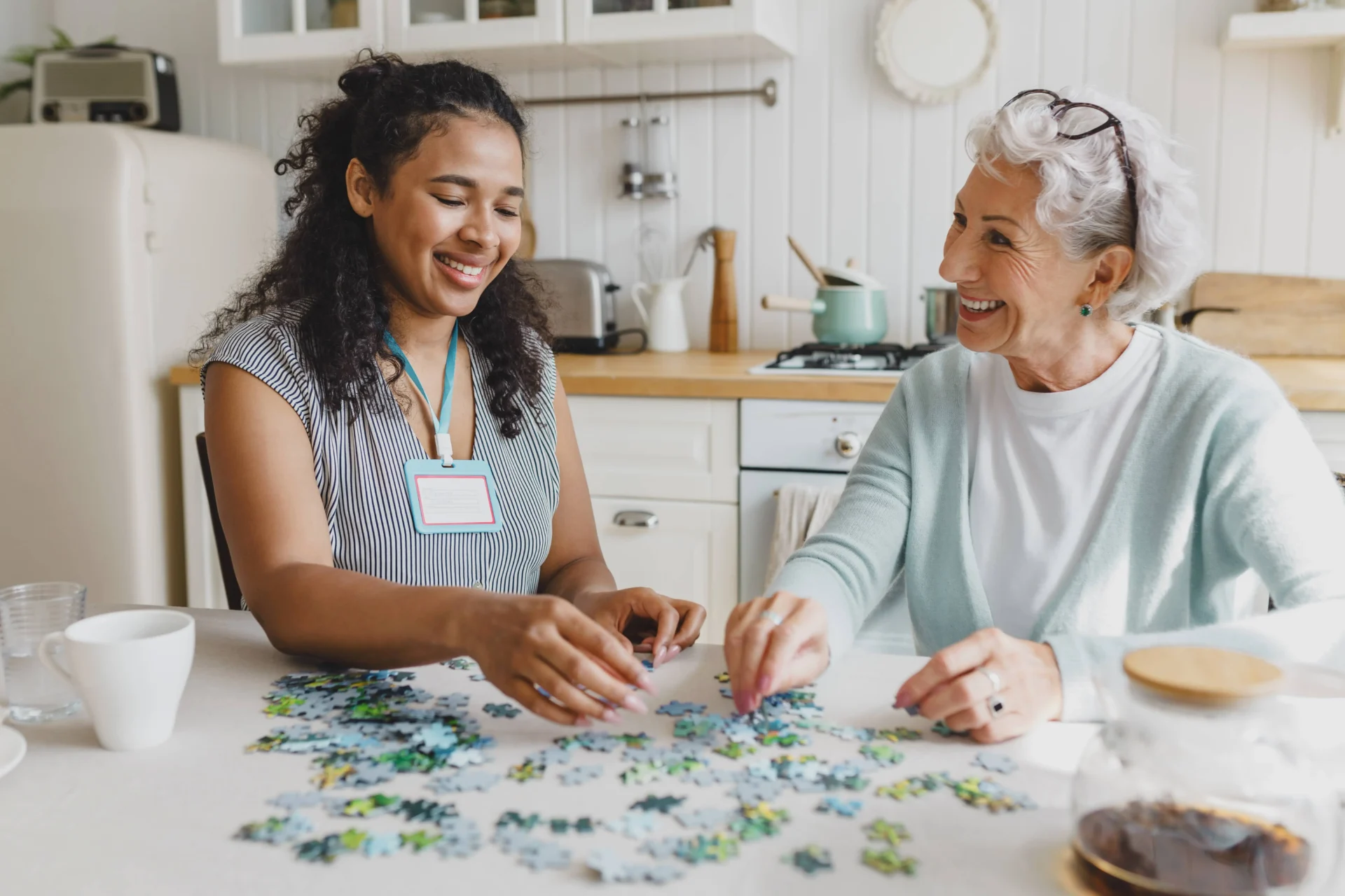 a person and a senior sitting at a table with a puzzle