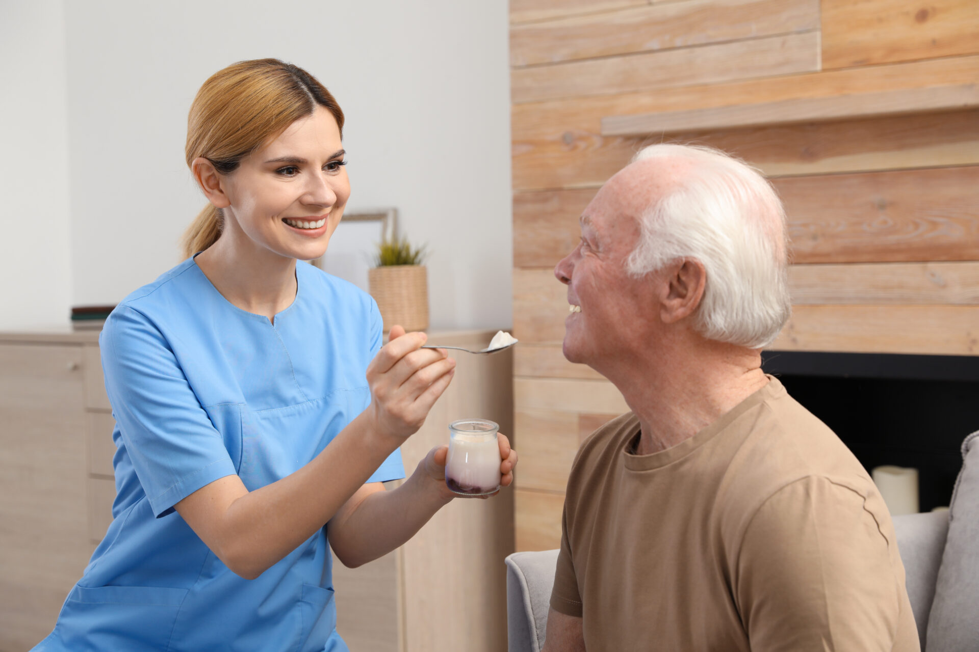caregiver feeding elderly man, providing post hospital care