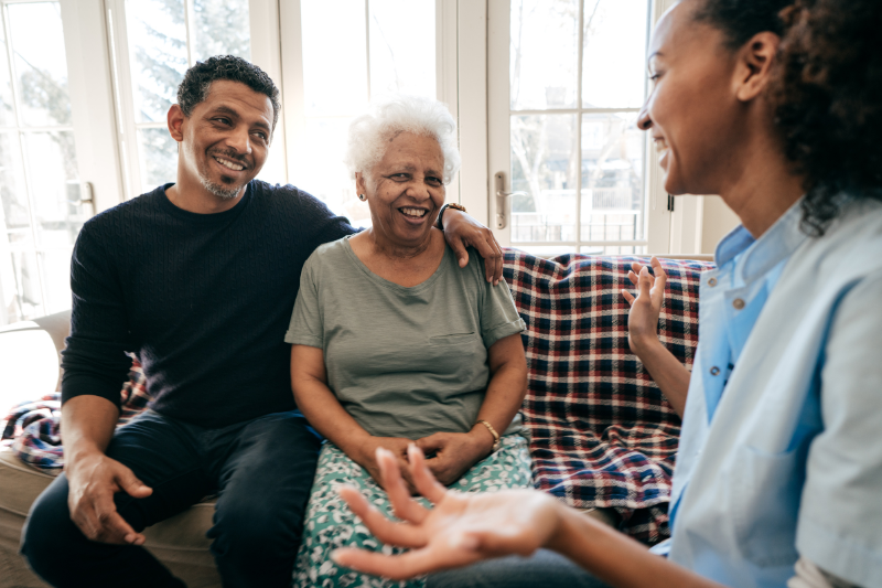 A man and woman sit on a couch with a senior, discussing home care in Chicago area