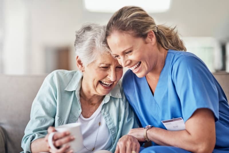 A caretaker and an older woman laughing together, showcasing qualified and divers caregivers in Chicago area.