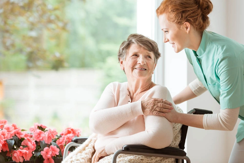 A caring nurse aids an elderly woman in a wheelchair, exemplifying high-touch ongoing support in healthcare.