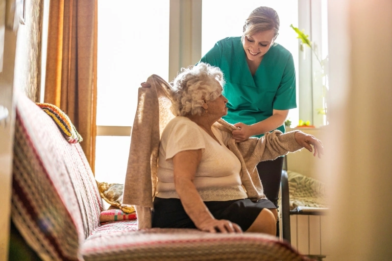 Driven by strong values, a caregiver gently places a cardigan over an elderly woman's shoulders.