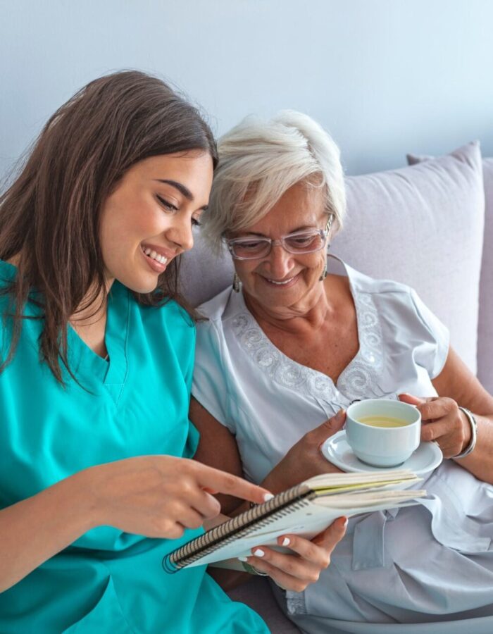 A caregiver reading to an elderly woman in care in nursing homes in Chicago area.