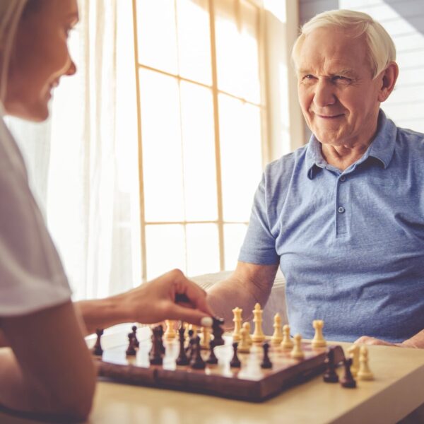 A chess match showcasing the bond between an older man and a caregiver in a care in nursing homes Chicago area.