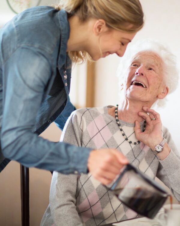 A woman helping an elderly lady with her meal at Respite Care Chicago area