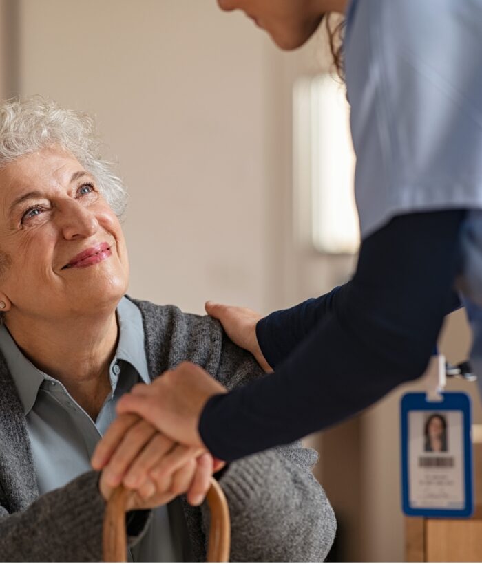 Supportive caregiver holds elderly woman's hand, assisting with chronic condition care in Chicago