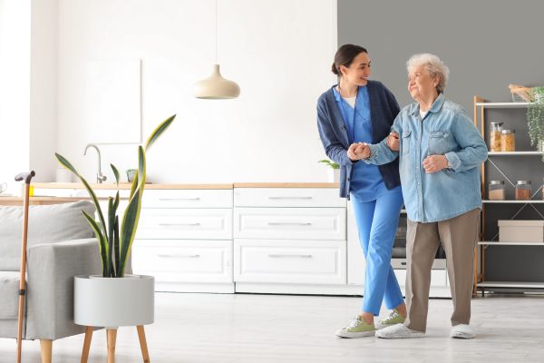 A caregiver and an elderly woman walk side by side in a living room, showcasing warmth and connection in hospice care at home Chicago area.